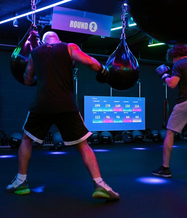 Man performing a strength exercise in a dark gym with blue lighting.